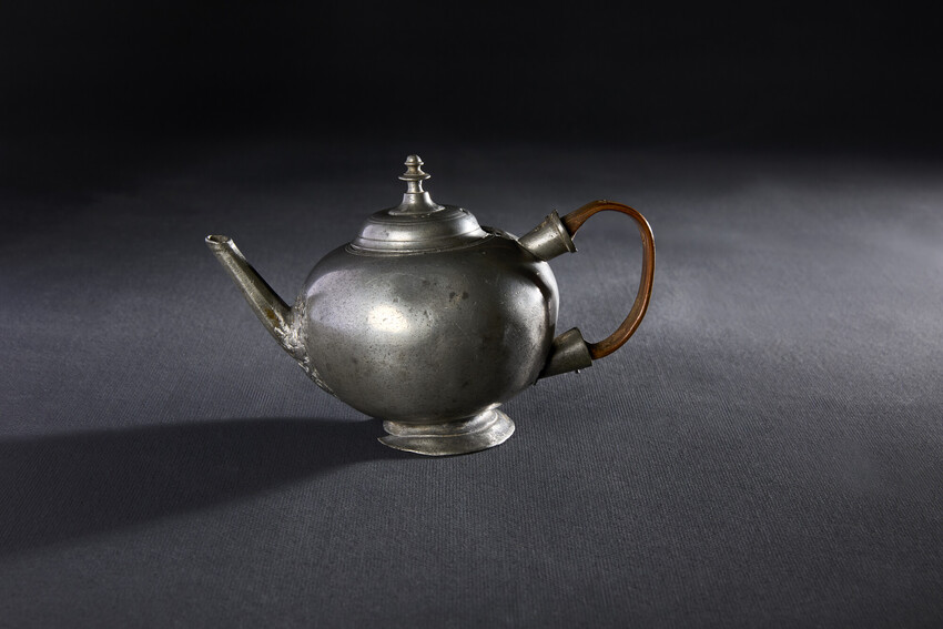A photo of a teapot sitting on a dark surface.