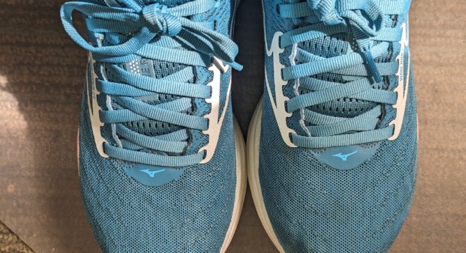 A top-down photo of a pair of turquoise running shoes. The wearer has black socks.